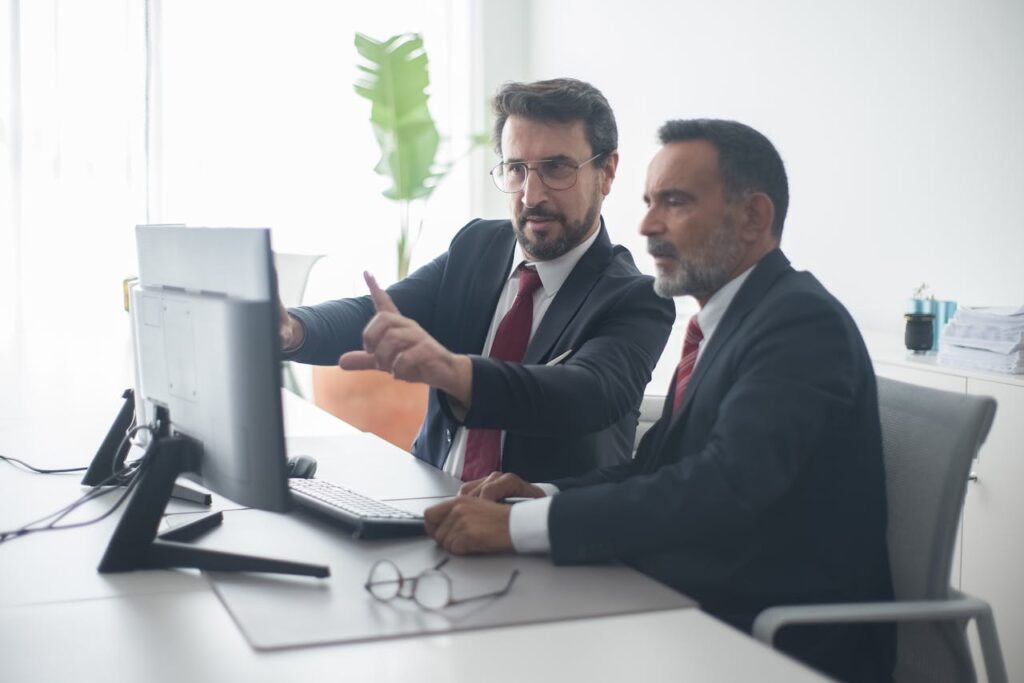 Two male colleagues collaborating on a project at the computer in a bright, modern office.